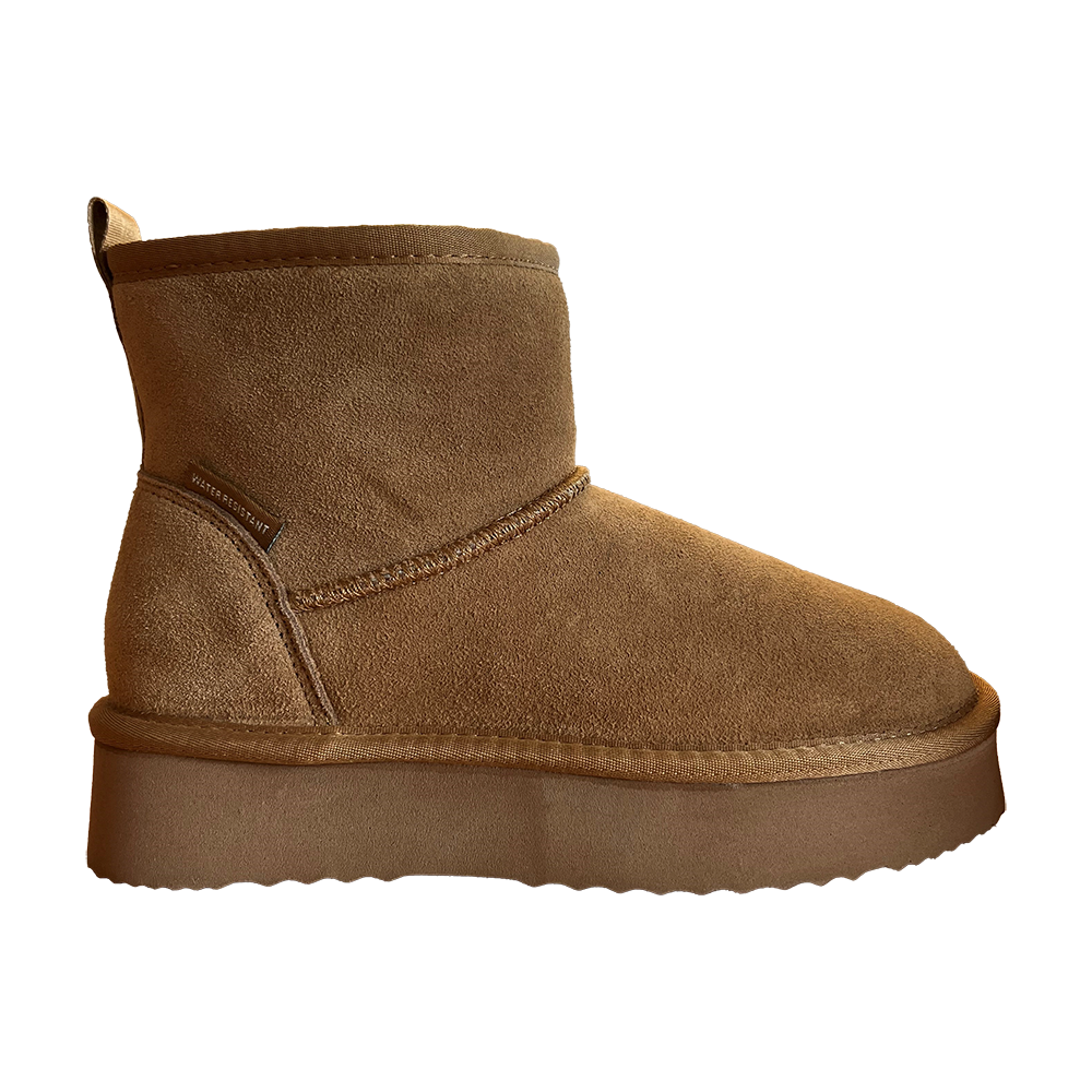 Brun ankelstøvle i blødt ruskind med enkel, minimalistisk silhuet. Støvlen har markant, tyk sål i gummi for ekstra højde og varme, tydelig syning langs overgangen og en lille "water resistant"-label ved hælen. Den lave skaft-højde gør den nem at tage på, og det afdæmpede design passer til både afslappede og vinterprægede outfits. En praktisk og stilren hverdagssko til kølige dage.