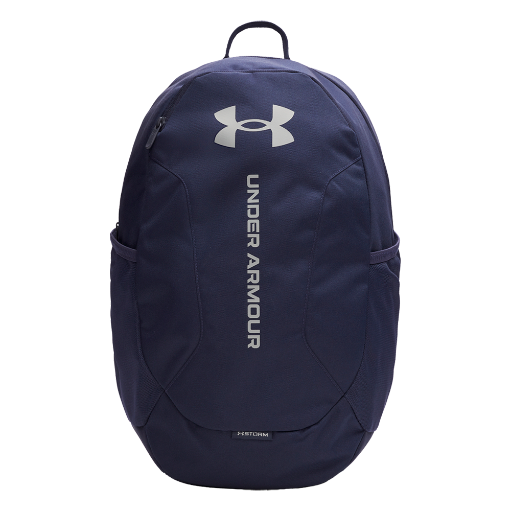 En navyblå rygsæk fra Under Armour med stort, hvidt logo øverst og vertikal 'UNDER ARMOUR'-tekst i midten. Den har en robust topstrop, glidelåslomme foran og to elastiske sidelommer til vandflasker. Materialet virker slidstærkt og vandafvisende ('Storm'-teknologi), hvilket gør den velegnet til skole, træning og hverdag. Enkel, funktionel og minimalistisk i sit design.