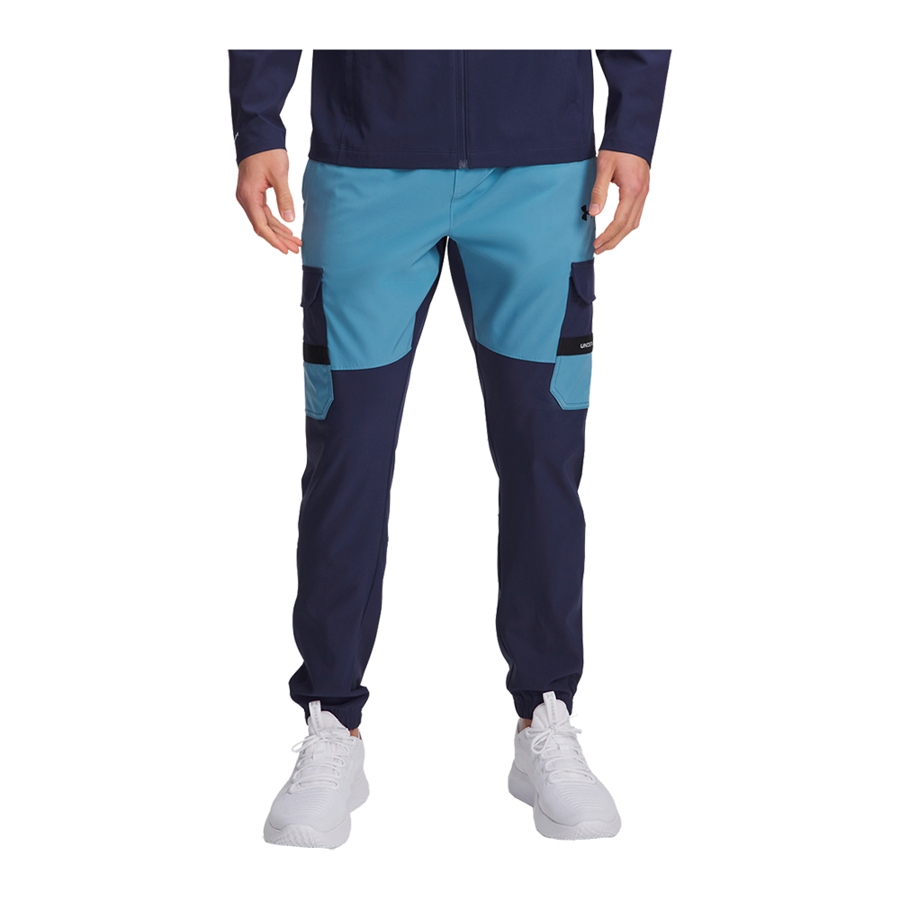 Billedet viser et par moderne, tofarvede herre-joggingbukser i navy og lys blå. Designet inkluderer rummelige cargolommer på lårene, kontrastpaneler og elastiske ankelmanchetter, hvilket giver et sporty og funktionelt udtryk. Bukserne har en slanke, afslappet pasform og bæres med hvide sneakers. Materialet virker teknisk og let, egnet til hverdag, træning eller casual fritid.