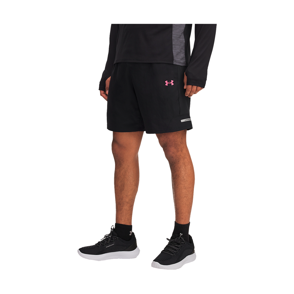 Et billede viser en person iført en sporty, sort trænings‑outfit fra midt lår til fødder. Personen har sorte løbeshorts med et pink logo, en langærmet sort træningstrøje, sorte ankelstrømper og sorte træningssko med hvide såler. Stående i afslappet, neutral position udstråler motivet klarhed og funktionalitet — passende til løb eller fitness, med en enkel og moderne æstetik.