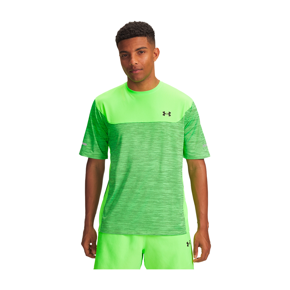 En ung mand står afslappet set forfra iført en skarpt neongrøn træningstshirt og matchende korte træningsshorts fra Under Armour. Overdelen har et lysere skulderparti og et tonet mønster på kroppen, mens logoet sidder diskret på brystet. Hans holdning er rolig og selvsikker, egnet til løb eller fitness, og farven giver et energisk og moderne udtryk.