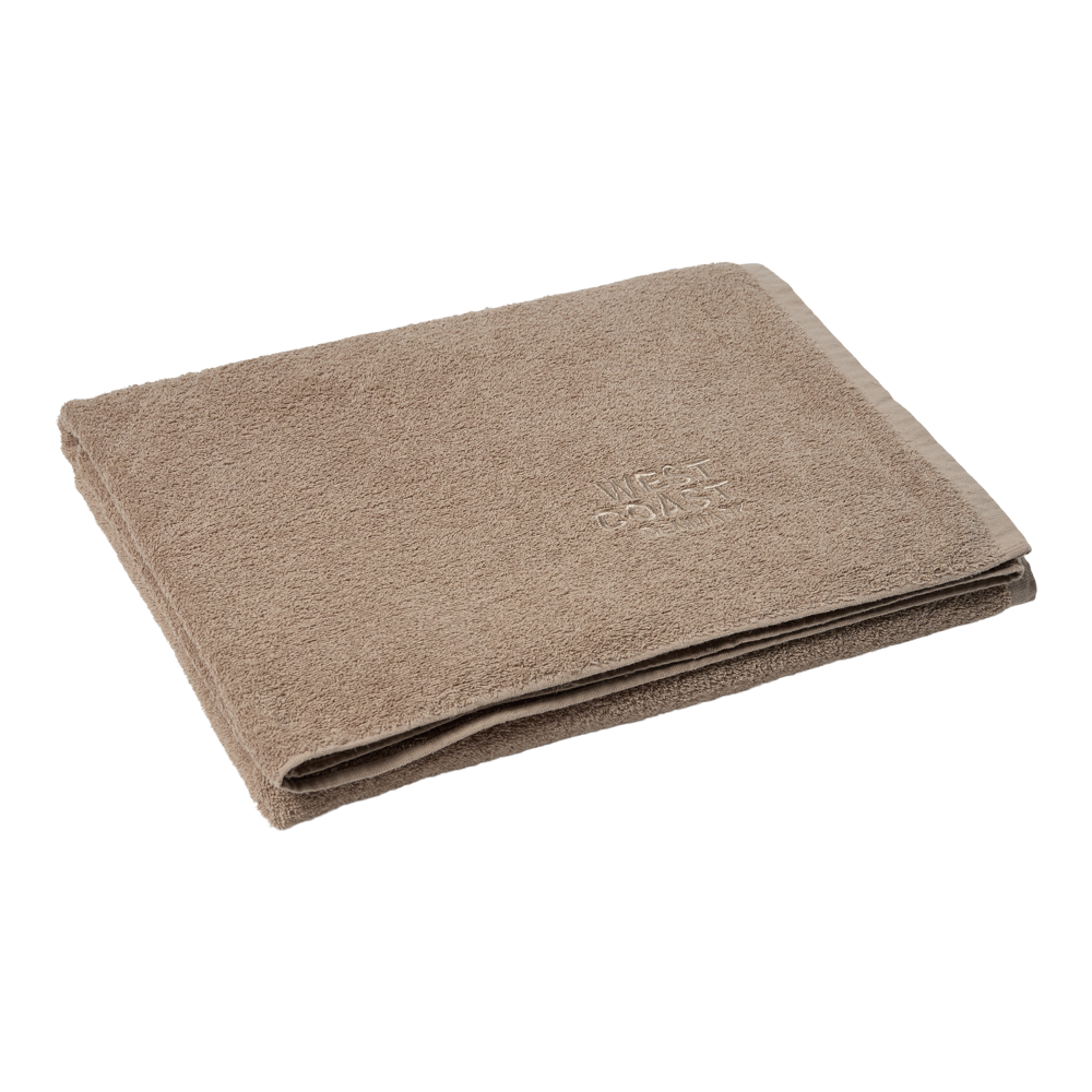 Et blødt, beige badehåndklæde er omhyggeligt foldet og lagt fladt mod en lys baggrund. Stoffet fremstår fyldigt og velplejet med tætte bomuldstresser, og en diskret indvævet tekstur og kantafslutning giver et enkelt, elegant udtryk. Håndklædet virker absorberende og komfortabelt, velegnet til både badeværelse og spa, og signalerer høj kvalitet og roligt design.
