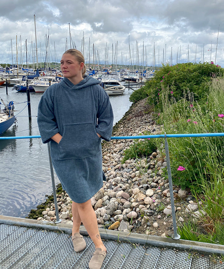 Denne West Coast Denmark Poncho LS 25, Uni - Voksen badekåbe i en stilfuld og komfortabel model er ideel til friluftsaktiviteter og afslapning ved stranden. Ponchoen er fremstillet i blødt materiale og har en praktisk hætte samt en stor lomme foran. Finishen er forbedret med et diskret logo fra West Coast Denmark på brystet, hvilket tilføjer et autentisk touch. Ponchoen er perfekt til enhver, der værdsætter funktionalitet og stil.