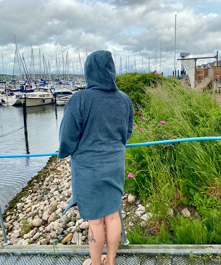 Denne badekåbe fra West Coast Denmark, betegnet som "West Coast Denmark Poncho LS 25", er til voksne og forener stil med funktionalitet. Designet i en behagelig blå farve, har badekåben en stor lomme på maven og en hyggelig hætte. Det stilfulde West Coast Denmark logo er tydeligt præsenteret på brystet. Ponchoen er ideel til brug efter en god svømmetur eller blot til afslapning derhjemme.