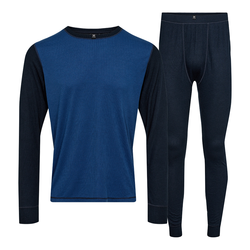 Langærmet sæt bestående af en tætsiddende trøje og matchende longjohns i ribstrikket materiale. Forsiden af trøjen er midnatsblå, mens ærmer og underdel er mørkere navy, hvilket giver et diskret, todelt udtryk. Den tætte pasform, ribstruktur og elastisk linning signalerer varme og bevægelsesfrihed, ideelt som svedtransporterende baselag under friluftstøj eller til afslappet komfort hjemme på kolde dage.