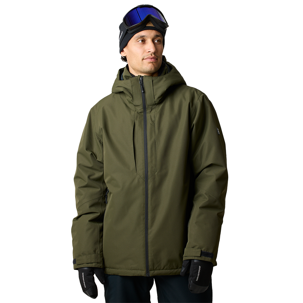 En ung mand står i en olivengrøn, polstret vinterjakke med højtstående krave og fastgjort hætte. Han bærer en sort hue og skibriller placeret på panden samt sorte handsker, hvilket giver indtryk af forberedelse til skiløb eller snowboarding. Jakken har en central lynlås og enkle, funktionelle detaljer; billedet fremhæver både varme og praktisk, minimalistisk design.