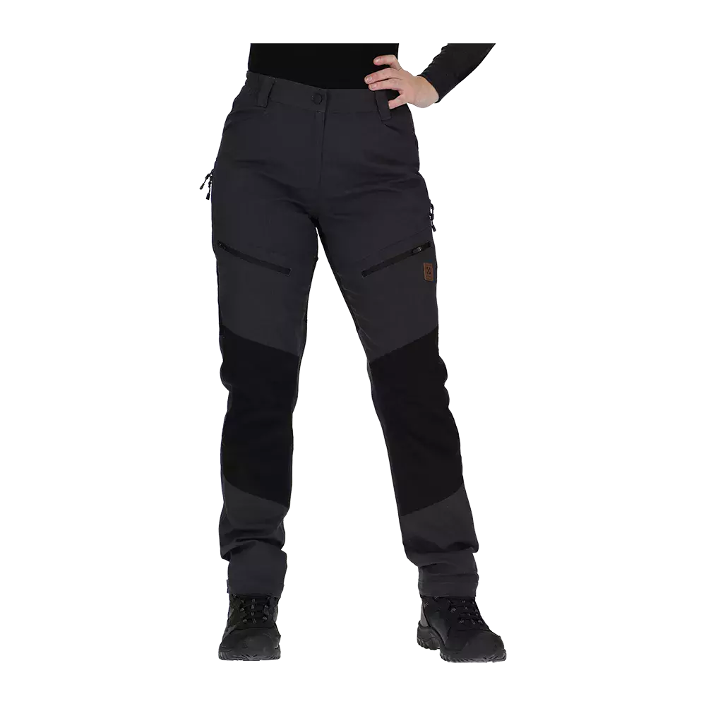 arbejdsbukser i mørkegrå og sort med funktionelle detaljer. Bukserne har forstærkede knæpartier, flere lommer med lynlås på lårene og bæltestropper ved livet. Den lige pasform og det kraftige materiale gør dem velegnede til udendørs aktiviteter, mens sorte støvler og en hånd på hoften understreger et praktisk og komfortabelt look.