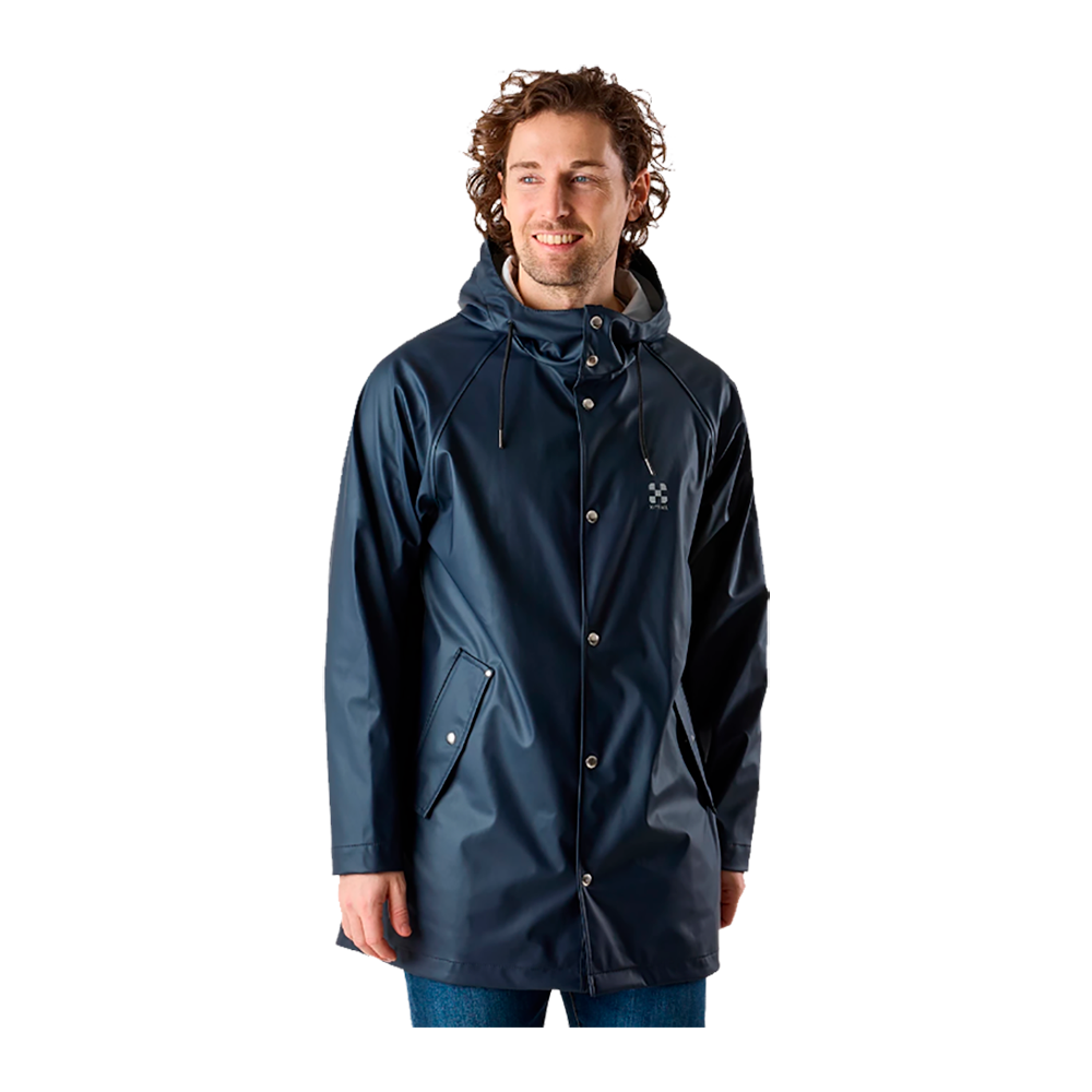 En ung mand står iført en mørkeblå regnjakke med hætte og trykknapper. Jakken har skrå lommer, et mat, vandafvisende materiale og en enkel, funktionel silhuet. Han smiler let og kigger til siden, hvilket giver et afslappet og naturligt udtryk. Kombinationen af praktisk design og minimalistisk detaljering gør jakken velegnet til hverdagens gråvejr og urbane ture i regnfuldt klima.