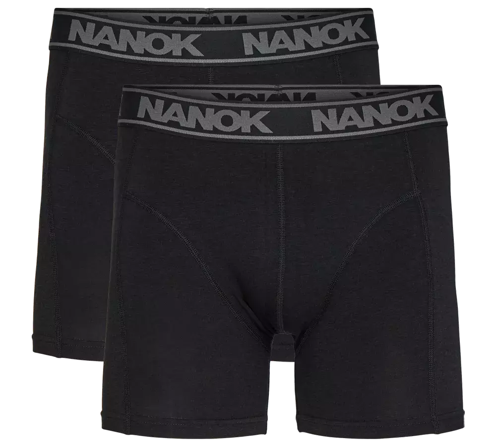 Billedet viser en dobbelpakke sorte boxershorts med længere ben og en bred elastiklinning prydet af det grå 'NANOK'-logo. Designet er enkelt og tidløst med flade syninger og formskærende paneler, der signalerer god støtte og komfort. Stoffet fremstår blødt og smidigt, velegnet til både hverdag og aktivitet. Et praktisk og stilrent valg til underdelen.