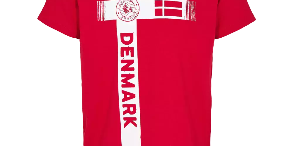 Rød t-shirt med et stort, hvidt korsprint på fronten, der tydeligt refererer til Dannebrog. På det lodrette kors står ordet "DENMARK" i fed, rødt typografi, og det tværgående felt indeholder en stiliseret dansk flaggrafik samt et rundt stempel med teksten "DENMARK". T-shirten har kortærmede, rund hals og et sporty, afslappet udtryk, velegnet til hverdagsbrug og nationale begivenheder.