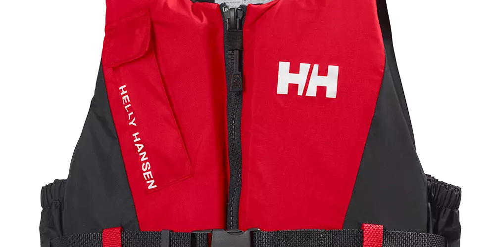 Rød og sort redningsvest fra Helly Hansen med tydeligt HH-logo på brystet. Vesten har centralt lynlås, justerbart sort bælte med hurtigspænde og elastiske sider for sikker pasform. Materialet virker robust og velegnet til sejlads eller vandsport, med lille lomme på venstre side og indvendig mærkat med vejledning. Designet kombinerer funktionalitet og høj synlighed på vandet.