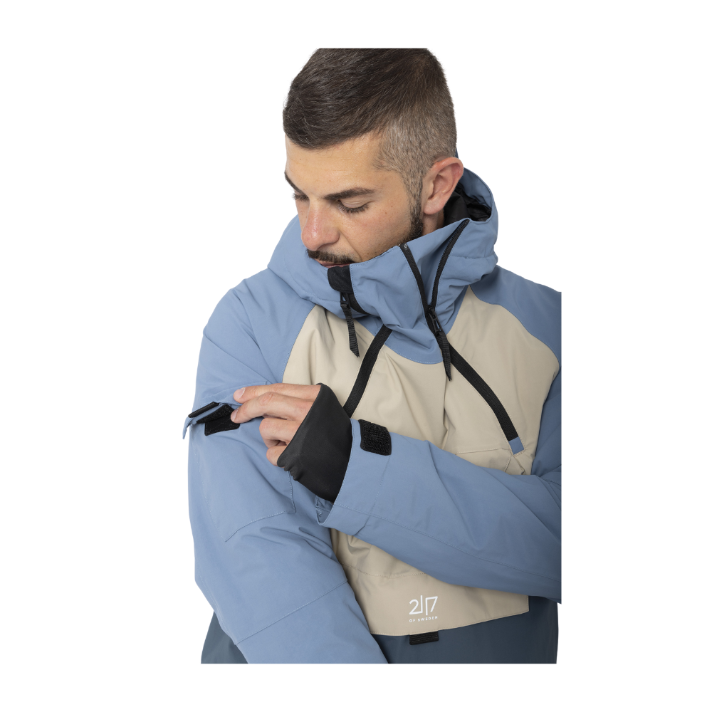 2117 of Sweden Nelkerim Padded Ski Anorak er den perfekte ledsager til skiture. Jakken er robust med et vandsøjletryk på 15.000 mm og åndbarhed på 15.000 g/m2, garanterende tør og komfortabel brug. Med sin PFC-fri imprægnering og strategisk tapede sømme beskyttes mod vind og vejr. Designet inkluderer en fast hætte, integreret snefang og en blanding af lommer, som sikrer praktisk opbevaring og nem adgang til vigtige ting under farten.