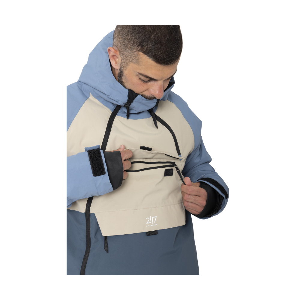 Denne 2117 of Sweden Nelkerim Padded Ski Anorak er en essentiel følgesvend for vinteraktiviteter. Dens blå og beige design giver et moderne look, mens den holdbare konstruktion med et vandsøjletryk på 15.000mm og åndbarhed på 15.000g/m2 lover optimal beskyttelse og komfort. Med PFC-fri imprægnering og ALTO-uldvattering sikrer jakken, at du forbliver varm og tør. Funktionelle detaljer som justerbare snore, elastiske manchetter og flere praktiske lommer forstærker dens anvendelighed på skiløjperne.