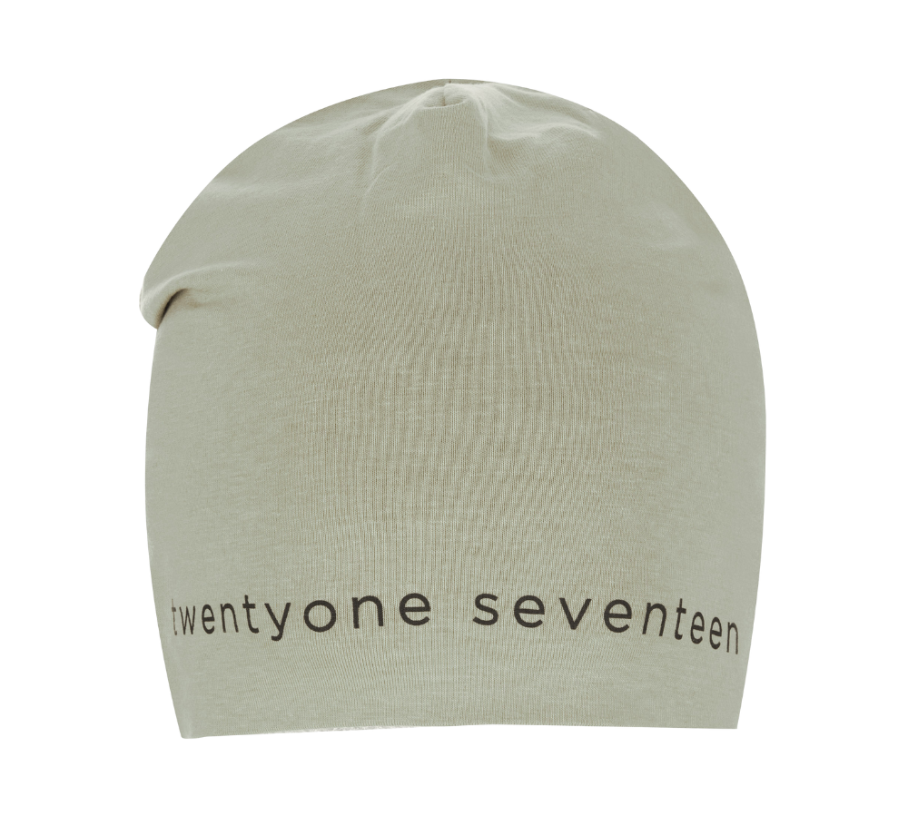 beige strikhue med et blødt, elastisk snit og let slouchy pasform. Langs nederkanten ses trykket 'twenty one seventeen' i enkle, sorte bogstaver, hvilket giver et minimalistisk og moderne udtryk. Huen virker lavet af fint ribstrikket stof, ideel til hverdagsbrug og køligere vejr. Den neutrale farve og rene typografi gør den nem at kombinere med jakker og afslappede outfits.