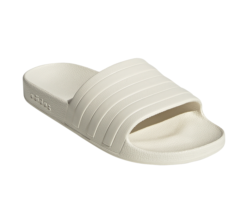 Et enkelt, hvidt slidesandal i let skumgummi med karakteristiske tre striber på remmen. Sandalen har en formstøbt fodseng med tekstureret overflade for bedre greb og en åben tå; den brede rem giver støtte. Materialet fremstår blødt og vandafvisende, velegnet til afslappet brug ved pool, strand eller hjemme. Designet er minimalistisk, praktisk og komfortorienteret.