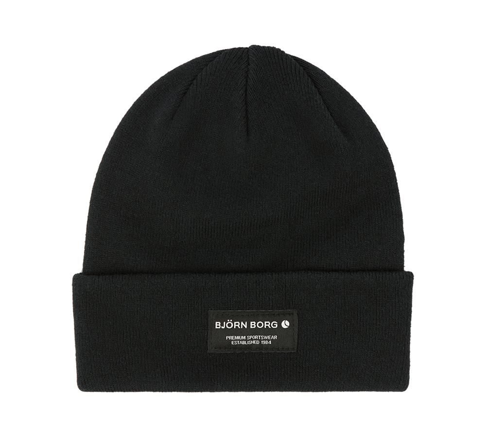 Sort, strikket beanie med opbukket kant og diskret mærke i front. Huen har et enkelt, minimalistisk udtryk; labelen viser "BJÖRN BORG" i hvid skrift mod mørk baggrund, hvilket giver et sporty og moderne præg. Den tætte strik og den klassiske form gør den velegnet til både hverdag og udendørs aktiviteter, og den passer nemt ind i en afdæmpet, urban garderobe.