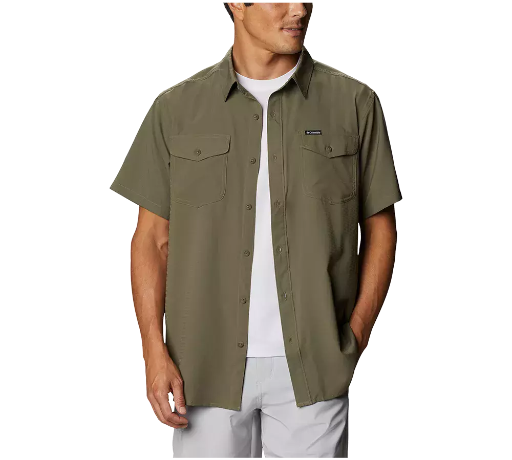 På billedet ses en mand iført Columbia Utilizer Solid Shirt, en herreskjorte i en stilfuld olivengrøn farve. Skjorten har korte ærmer, ideelle til summereventyr. Udformet med klassisk knapåbning og skjortekrave, har den to brystlommer med knaplukning og et afrundet kant forneden, hvilket tilføjer til dens afslappede udseende. Skjorten er designet med Omni-Wick™ teknologi, der hjælper med at regulere kropstemperaturen og holde bæreren kølig på varme dage.