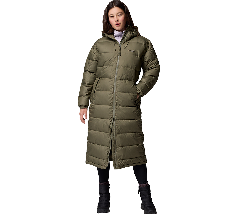 En kvinde står i en lang, olivengrøn dunfrakke med hætte og synlige vandrette quilt-sømme. Frakken når næsten til anklene, har en gennemgående lynlås, indbyggede sidelommer og en afslappet, varm silhuet. Under bærer hun sorte leggings og vinterstøvler, hvilket skaber et praktisk og komfortabelt vinterlook. Modellen har en rolig, neutral holdning, som fremhæver jakken som billedets hovedfokus.