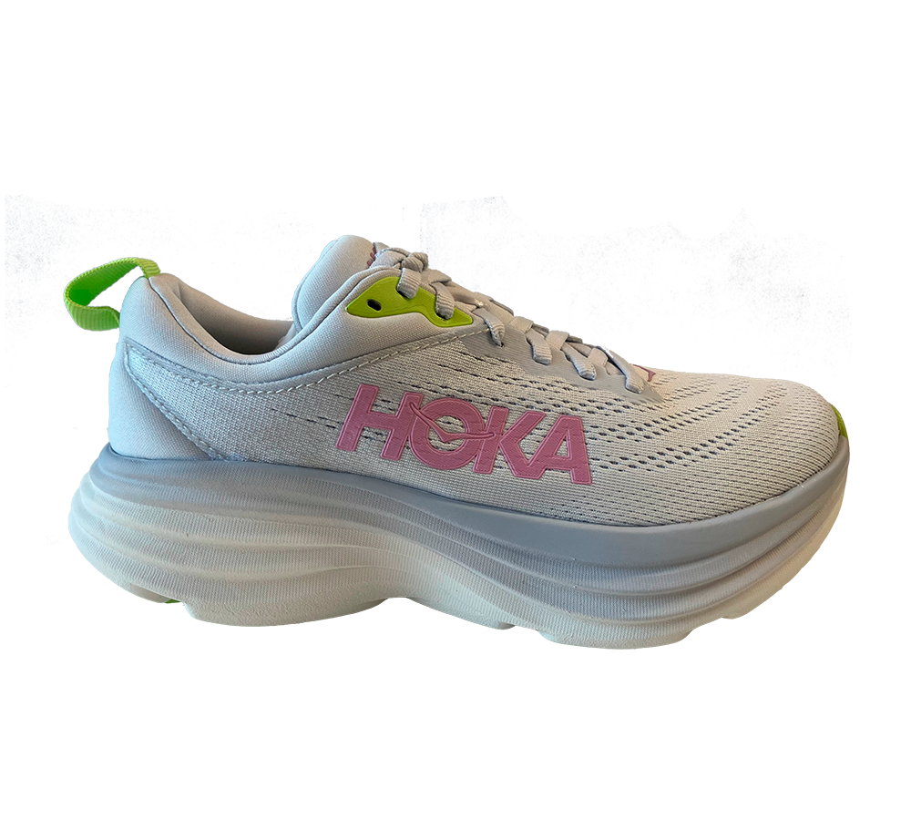 Et ensfarvet, lyst løbesko fra HOKA med markant lyserødt logo på siden og små neongrønne detaljer ved snørehuller og hælkappe. Overdelen er i åndbart mesh med subtile perforeringer, mens den kraftige, bølgende mellemsål giver ekstra affjedring og højde. Skoen har klassisk snørebånd, polstret krave og en praktisk hæl-loop, hvilket giver et moderne, komfortorienteret og stabilt udtryk til både træning og hverdag.