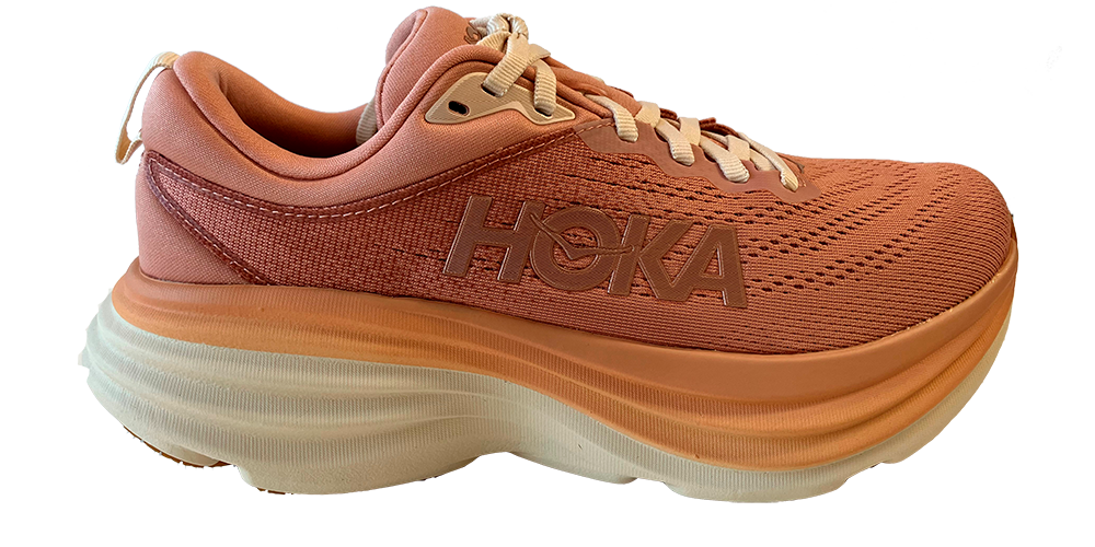 Et koralfarvet Hoka-løbesko ses fra siden med kraftig, ekstra polstret sål i lag af orange og creme. Overdelen er i åndbar mesh med fine syninger og HOKA-logoet trykt på siden. Skoen har flade beige snørebånd, blød hælkappe og et let, affjedrende design, der signalerer komfort og stabilitet til lange løbeture eller hverdagsbrug.