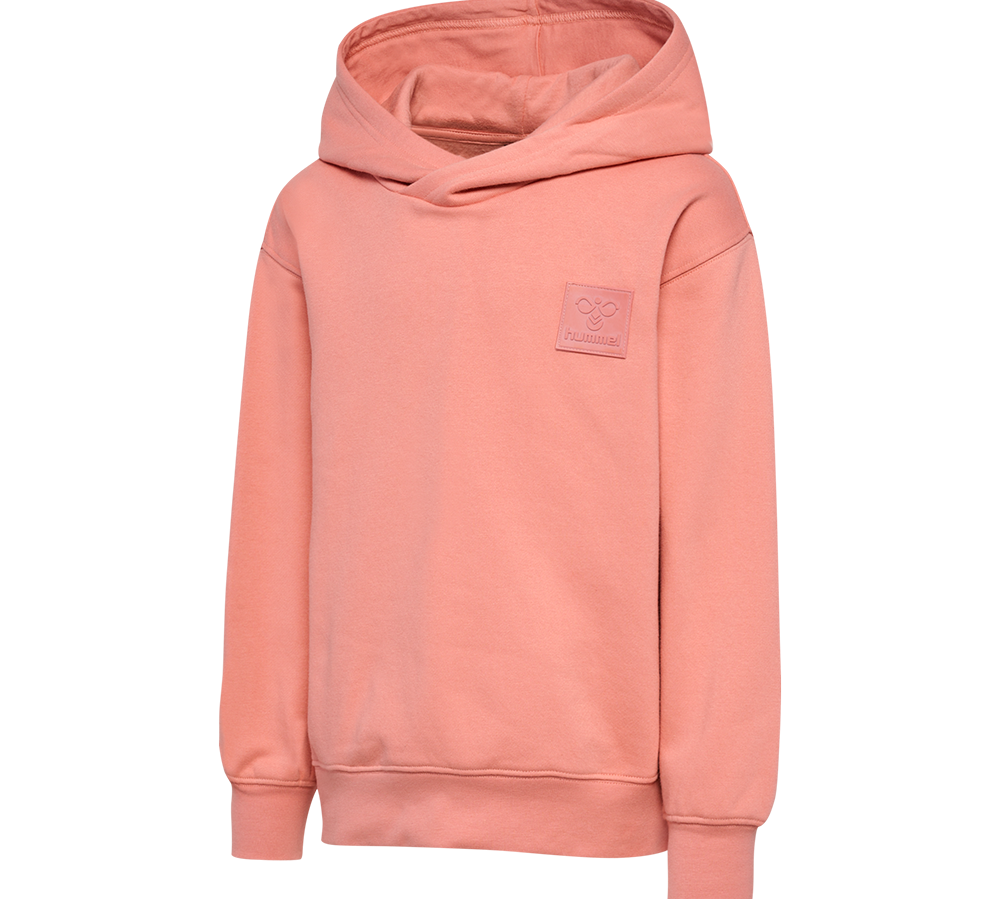 En blød, laksefarvet hættetrøje med et enkelt og minimalistisk udtryk. Modellen er en pullover uden synlige lommer, med en diskret firkantet logo-patch på brystet. Hætten er rummelig, og trøjen har ribkanter ved ærmer og kant samt let dropped shoulders for et afslappet fit. Stoffet virker som børstet sweatstof, der lover varme og komfort til hverdagsbrug.