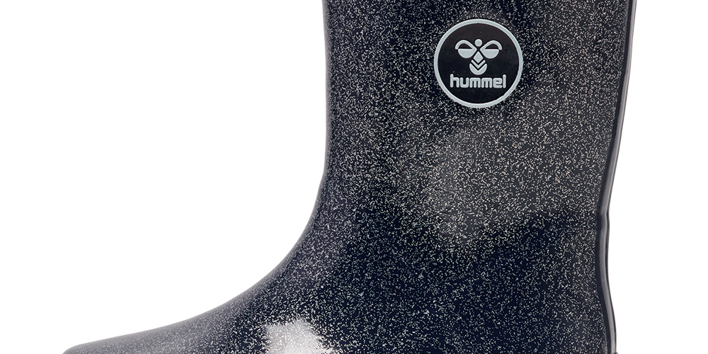 Et enkelt, mørkeblåt gummistøvle med diskret glimmerpræg og blank overflade. Støvlen har en kraftig, skridsikker sål, opret skaftekant og en lille trækrem bagtil for nem påtagning. På ydersiden ses en rund hummel-logo, som giver et sporty udtryk. Praktisk til regnvejr og mudder, kombinerer den funktionalitet med et stilrent, legende design og komfort.