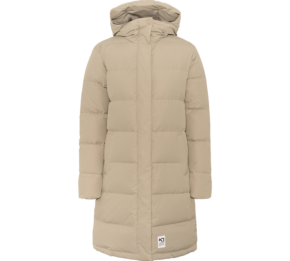 Lang, vatteret frakke i en varm beige tone med hætte og skjult lukning. Den enkle, quiltede konstruktion giver et rent, tidløst udtryk, mens sidelommerne og længden sikrer funktionel varme på kolde dage. Frakken virker kønsneutral i snittet og er ideel til hverdag eller byliv, hvor komfort og diskret stil prioriteres.