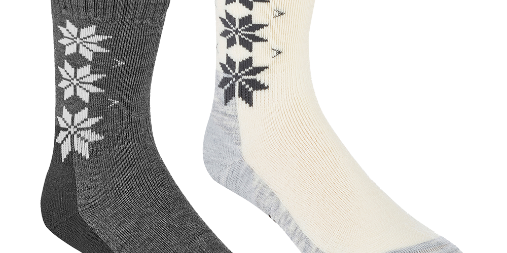 Billedet viser et par tykke vinterstrømper i forskelligt design. Den ene er mørkegrå med hvide nordiske stjernemønstre langs siden, den anden er cremefarvet med mørke stjerner og lysegrå forstærkede hæl- og tåpartier. Begge strømper har ribbet skaft, blød, tætvævet struktur og forstærkninger ved belastede områder. De udstråler varme og komfort og passer godt til koldt vejr eller hyggehjemmebrug.