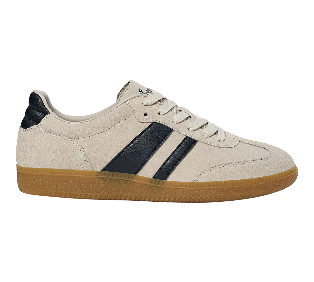 En lav, klassisk sneaker i lyst beige ruskind med to mørkeblå striber langs siden og matchende hælkappe. Skoen har flade, hvide snørebånd, dekorative syninger og en gennemskinnelig, lysebrun gummisål med tekstureret mønster. Den enkle, retroinspirerede silhuet giver et tidløst, afslappet udtryk, velegnet til både hverdag og fritid, og kombinerer komfort med et stilrent, sporty look.