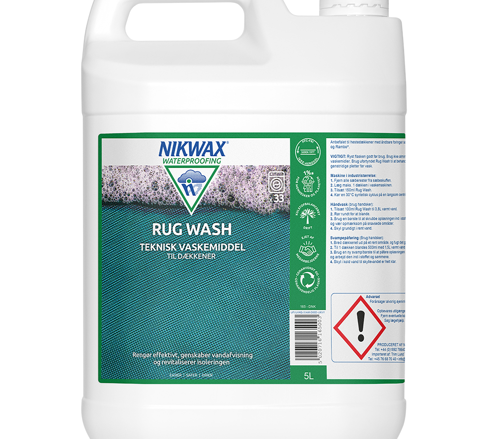 På billedet ses en hvid 5-liters plastdunk fra NIKWAX med produktnavnet "Rug Wash" — et teknisk vaskemiddel til dækkener. Et grønt og turkis label viser skum- og teksturmotiv, brandlogo og detaljerede vaskeanvisninger. En farepiktogram og brugsvejledning er tydeligt placeret på siden. Emballagen signalerer professionel rengøring og genopfriskning af vandafvisning til udendørs tekstiler, med praktisk bærehåndtag og skruelåg.