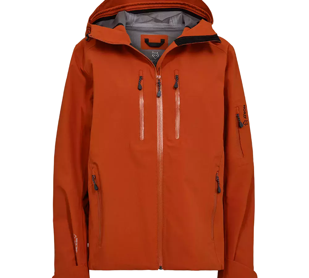 En moderne, teknisk jakke i brændt orange med hætte og høj krave. Designet har to lodrette brystlommer med vandtætte lynlåse, sidelommer og en lommeklappe på ærmet. Indvendig ses en lys grå foret kant, og materialet virker robust og vind- og vandafvisende. Justerbare manchetter og en central lynlås fuldender et funktionelt og stilrent outdoor-look, ideelt til vandring eller hverdag i dårligere vejr.