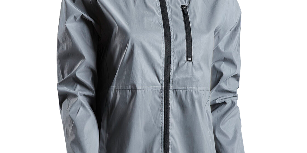 En let, grå vind- og regnjakke med hætte og sort gennemgående lynlås. Jakken har en vandafvisende, mat overflade, en lodret brystlomme med lynlås og elastiske ærmeafslutninger. Synlige sømme i taljehøjde og en simpel, funktionel silhuet gør den velegnet til udendørs aktiviteter og hverdag. Det minimalistiske design fokuserer på praktisk beskyttelse mod regn og vind.