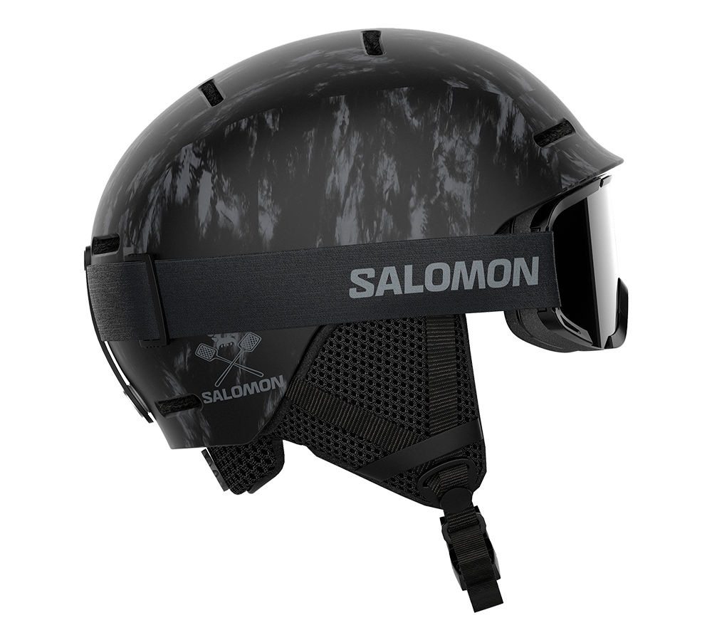 Et moderne sort skihjelm fra Salomon med et diskret marmoreret mønster og integreret goggle-strop med brandlogo. Hjelmen har ventilationsåbninger på toppen, polstrede øreklapper i mesh og en justerbar hagespænde for sikker pasform. Det slanke design kombinerer beskyttelse og komfort til alpint skiløb eller snowboard, og den passer perfekt til både fritids- og erfarne skiløbere.
