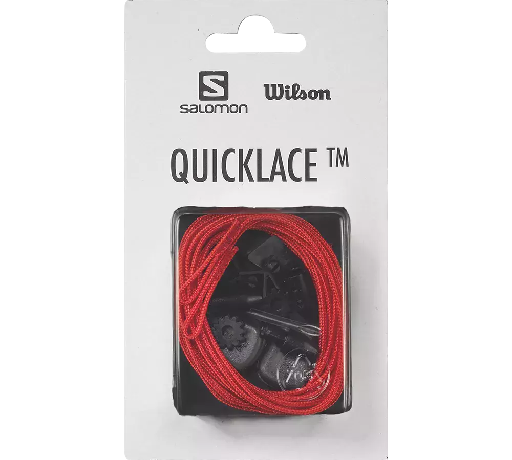 På billedet ses en forpakning til Quicklace-systemet fra Salomon og Wilson. Hvidt papkort med logoer øverst og teksten "QUICKLACE TM". Gennem en gennemsigtig plastvindue ligger et rødt elastisk snørebånd rullet sammen med sorte plastspoler og låsemekanismer til hurtig justering. Produktet fremstår som en praktisk udskiftningsløsning til sko, der kræver nem og hurtig spænde- og løsnefunktion.