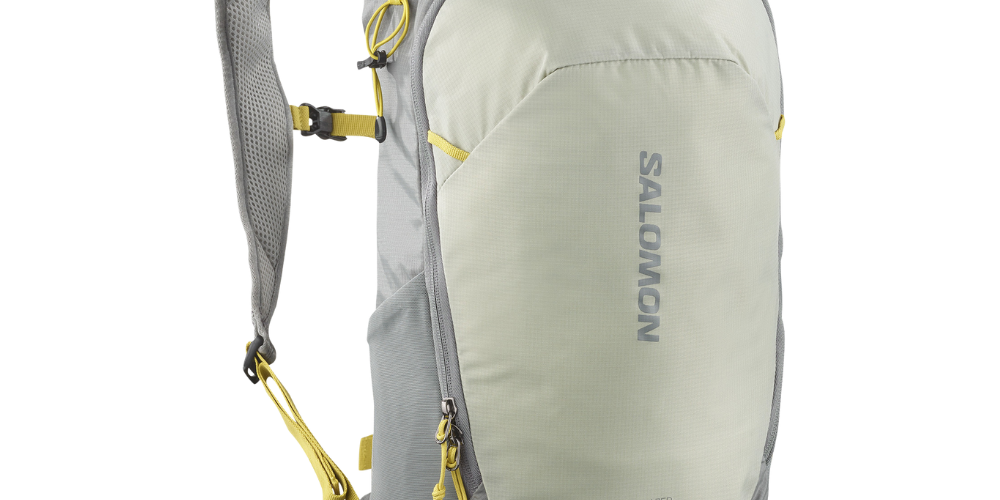 grøn rygsæk fra Salomon med synligt logo og gule detaljer. Trailblazer 10-modellen har et slankt, ergonomisk design med polstrede, ventilerede skulderstropper, justerbar brystrem og små hofte- og sidelommer. Flere lynlåslommer og elastiske stropper giver hurtig adgang til udstyr, mens slidstærkt ripstop-agtigt materiale og forstærket bund sikrer holdbarhed. Perfekt til dagsture og løbeture.