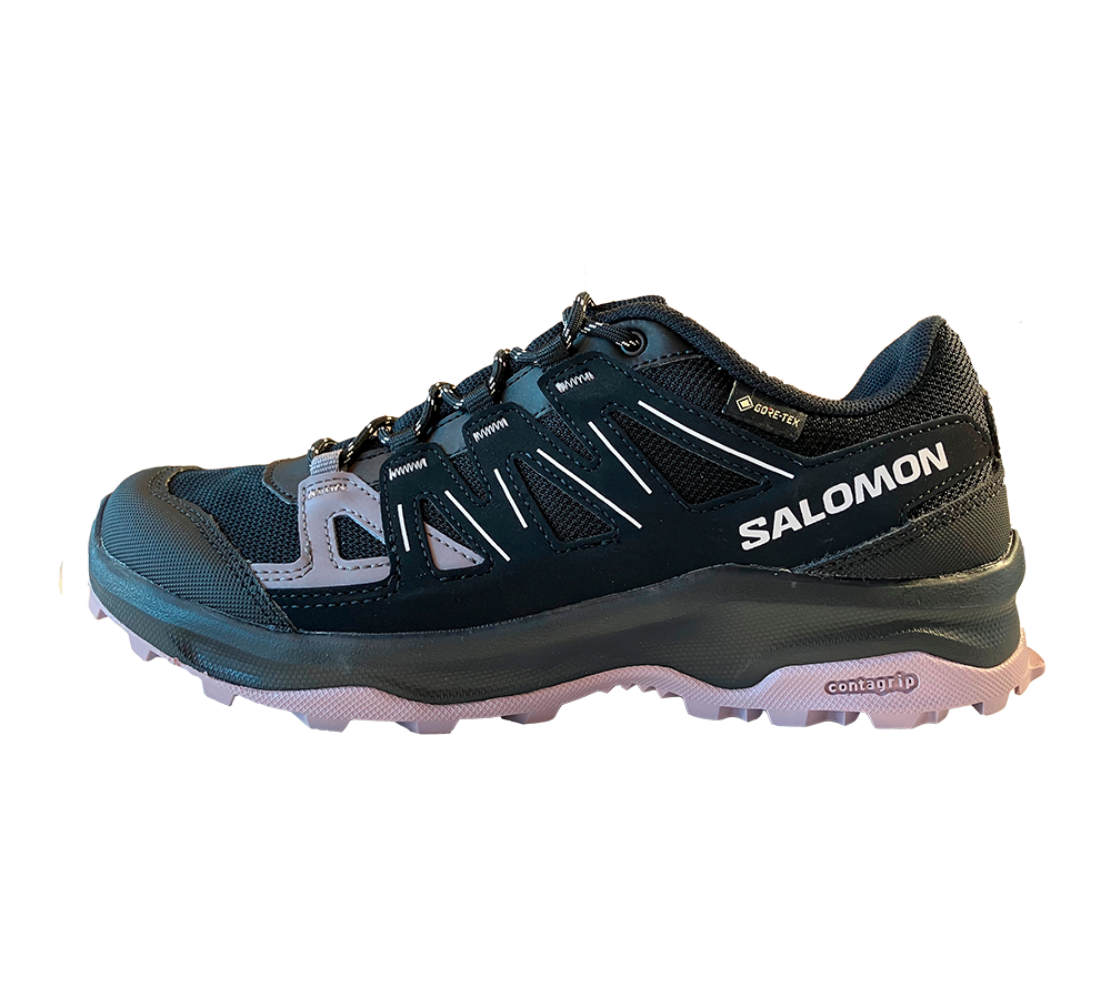Et robust Salomon trail-sneaker i sort med lyserød sål, designet til udendørs brug. Skoens mesh- og syntetiske overdel kombinerer åndbarhed og støtte, mens Gore‑Tex-mærket indikerer vandtæt beskyttelse. Forstærket tåområde, sikrede snørebånd og mellemsål giver komfort og stabilitet. Contagrip-ydersålen sikrer godt greb på ujævne stier, hvilket gør skoen velegnet til både vandring og aktiv fritid.