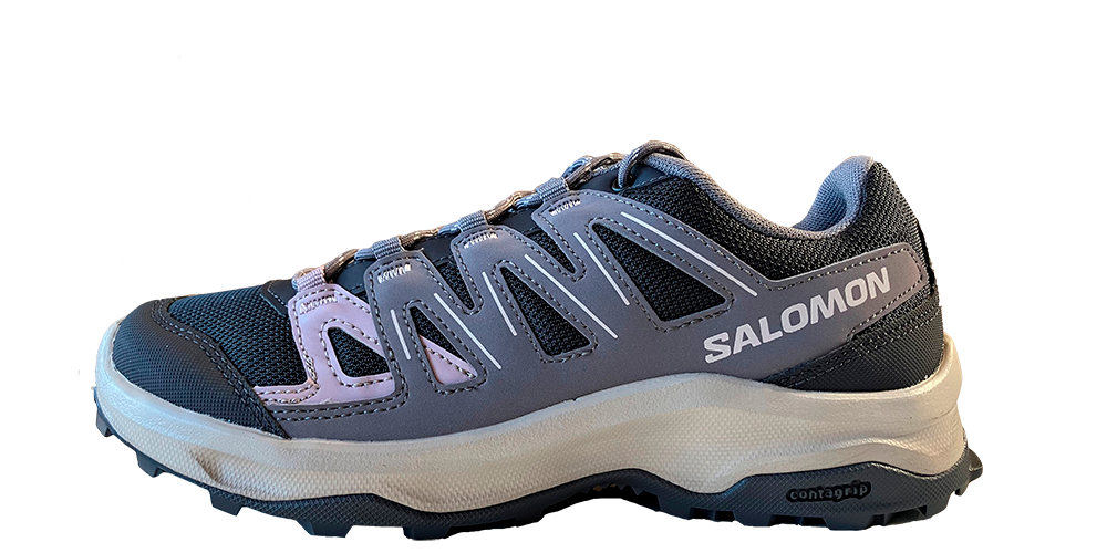 Et gråligt Salomon-sportsko med lyserøde detaljer og ventilationsmesh i tå- og mellemfodsområdet. Skoen har syntetiske forstærkninger og klokkeformede paneler for støtte, klassisk snøresystem og polstret hælkappe. Den hvide, stødabsorberende mellemsål hviler på en kraftig, mørk Contagrip-yderdel med tydeligt mønster for greb. Skoen fremstår robust, allround og velegnet til vandring og aktive udendørsaktiviteter.