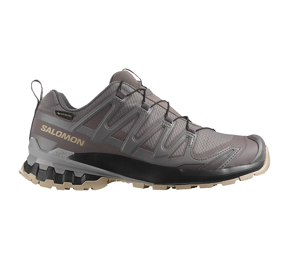 Dette er en robust Salomon vandresko i dæmpede grå- og brune nuancer med tydelig Salomon-logo og GORE-TEX-mærke. Skoen har et lavt snit, holdbar overdel og et avanceret snøresystem for sikker pasform. Den aggressive, multidirektionelle ydersål og polstrede mellemsål giver greb og stødabsorbering på ujævnt terræn. Velegnet til lange ture i vådt og kuperet terræn.
