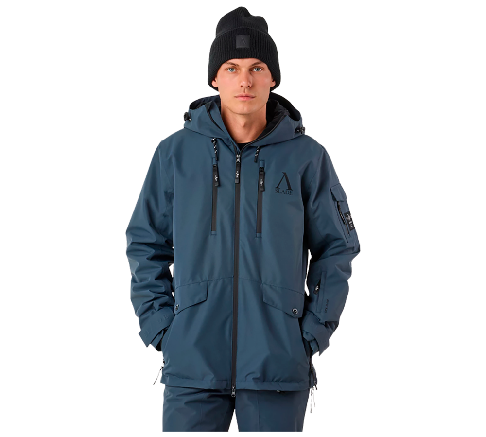 På billedet ses en ung mand iført Slade Aspen Jacket II Sr, en alsidig herre vinter- og skijakke fra Slade. Jakken, i en formindskende blå farve, fremstår teknisk avanceret med dens mange funktionelle lommer og justerbare træk på hætte og talje. Den er designet til at modstå ekstreme vejrforhold, hvilket understreges af de vandtætte lynlåse og tapede sømme. Han bærer også en sort strikhue, som komplementerer det robuste vinterudstyr og tilføjer et ungdommeligt touch.