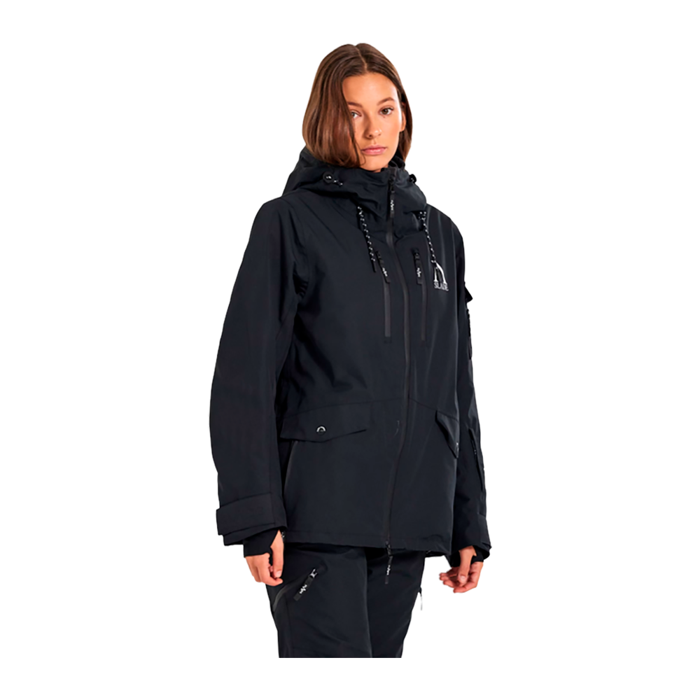 Denne billede viser en kvinde iført "Slade Aspen Jacket W", en skijakke designet til damer. Jakken, der er fremstillet af Slade, fremstår i en klassisk sort farve, der tilføjer et stilfuldt, men praktisk element til vintergarderoben. Denne model har flere funktionelle detaljer såsom justerbare snore, rummelige lommer, og en robust hætte, der yder optimal beskyttelse mod vind og vejr, ideel til skiløb eller vinterbrug.