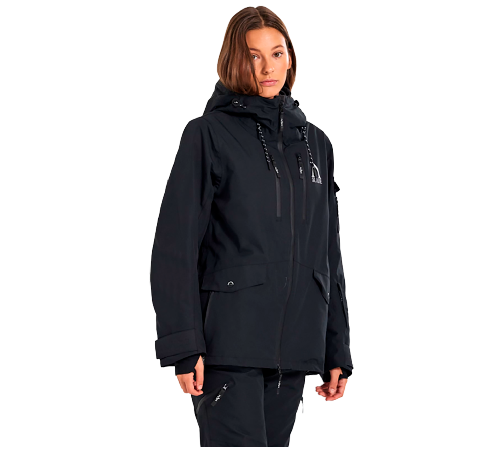 Denne billede viser en kvinde iført "Slade Aspen Jacket W", en skijakke designet til damer. Jakken, der er fremstillet af Slade, fremstår i en klassisk sort farve, der tilføjer et stilfuldt, men praktisk element til vintergarderoben. Denne model har flere funktionelle detaljer såsom justerbare snore, rummelige lommer, og en robust hætte, der yder optimal beskyttelse mod vind og vejr, ideel til skiløb eller vinterbrug.