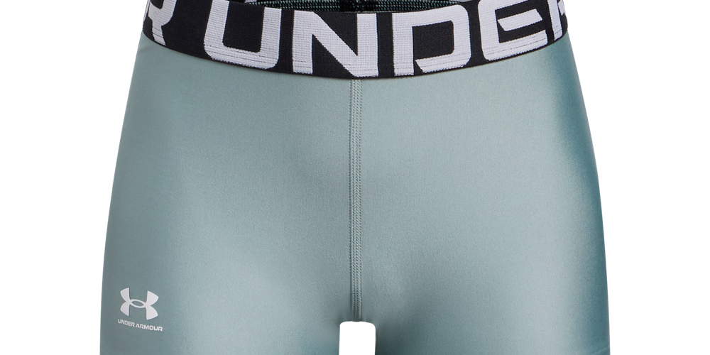 Et par korte, tætsiddende træningsshorts i en mat mintgrøn farve. Materialet virker glat og elastisk med en tæt pasform, der fremmer bevægelsesfrihed. Den brede sorte linning har stor, hvid 'UNDER' tekst, og Under Armour-logoet findes diskret på venstre lår. Designet er minimalistisk og funktionelt, velegnet til løb, styrketræning eller højintensiv træning.