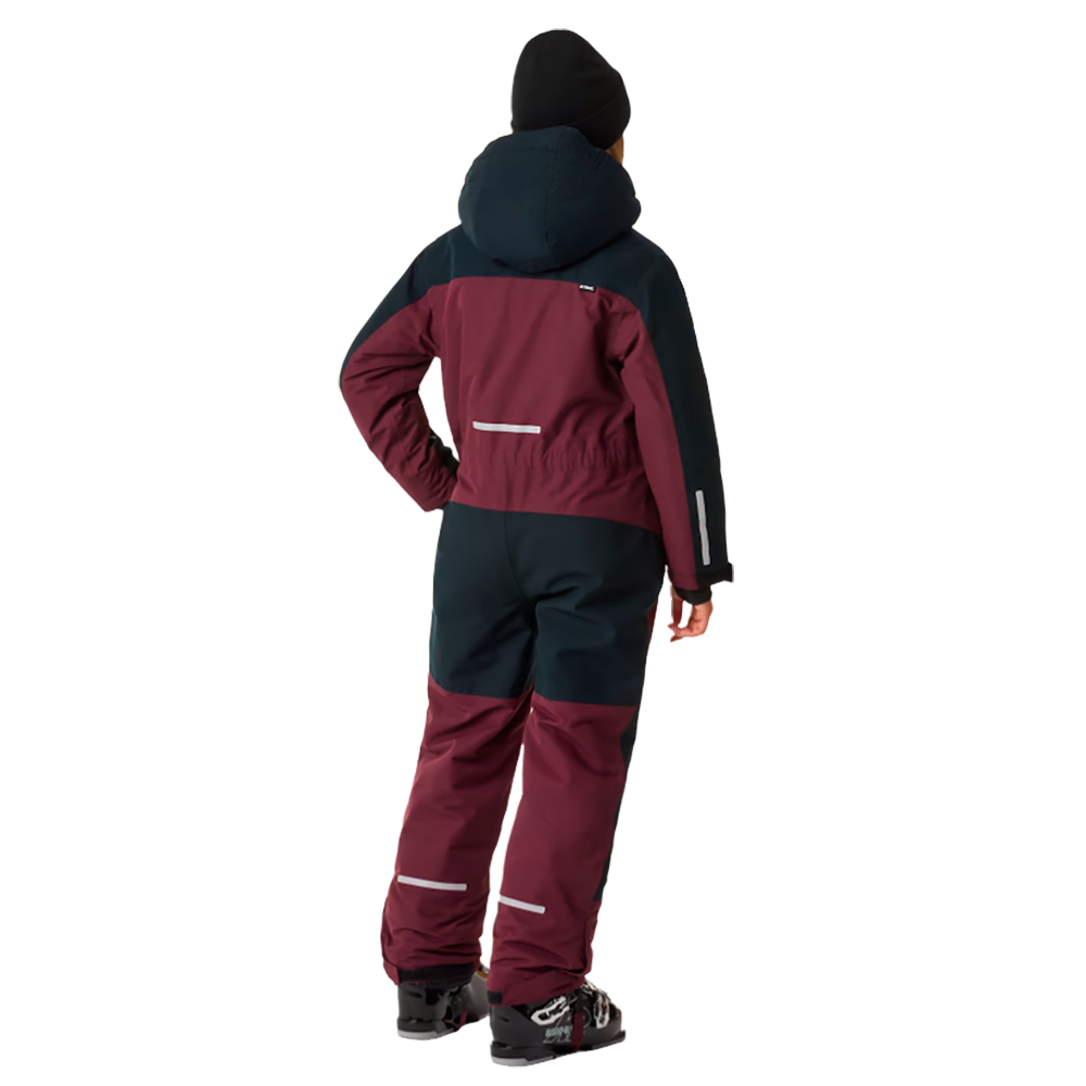 Barnet på billedet er iført X-TRAIL Cortina Overall Jr, en børneflyverdragt fra X-Trail, designet til at holde de små varme og komfortable i koldt vejr. Dragten har en mørkerød farve med mørkeblå detaljer og er fremstillet i vandtætte materialer med refleksstriber for ekstra sikkerhed. Denne praktiske flyverdragt er ideel til vinterens eventyr og udendørs leg.